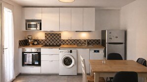 Een kleine keuken met een wasmachine, oven, magnetron en koelkast.