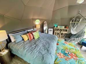 A tent-style room with a bed, a desk, a chair, and a hanging chair. - Naut on Call Geodome at The Edge—Unique Riverfront Glamping in Salt Lick, KY (Salt Lick)