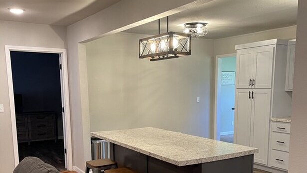 Una cocina moderna con barra, suelo de madera y un sofá gris en la sala de estar.