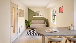 Een moderne woonkamer met een bank, een eettafel en een keukenhoek.