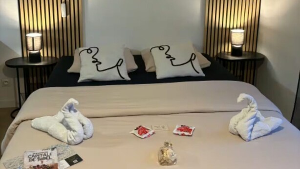 Ein Hotelzimmer mit einem Bett, zwei Nachttischen, einem an der Wand befestigten Schild und Handtüchern.