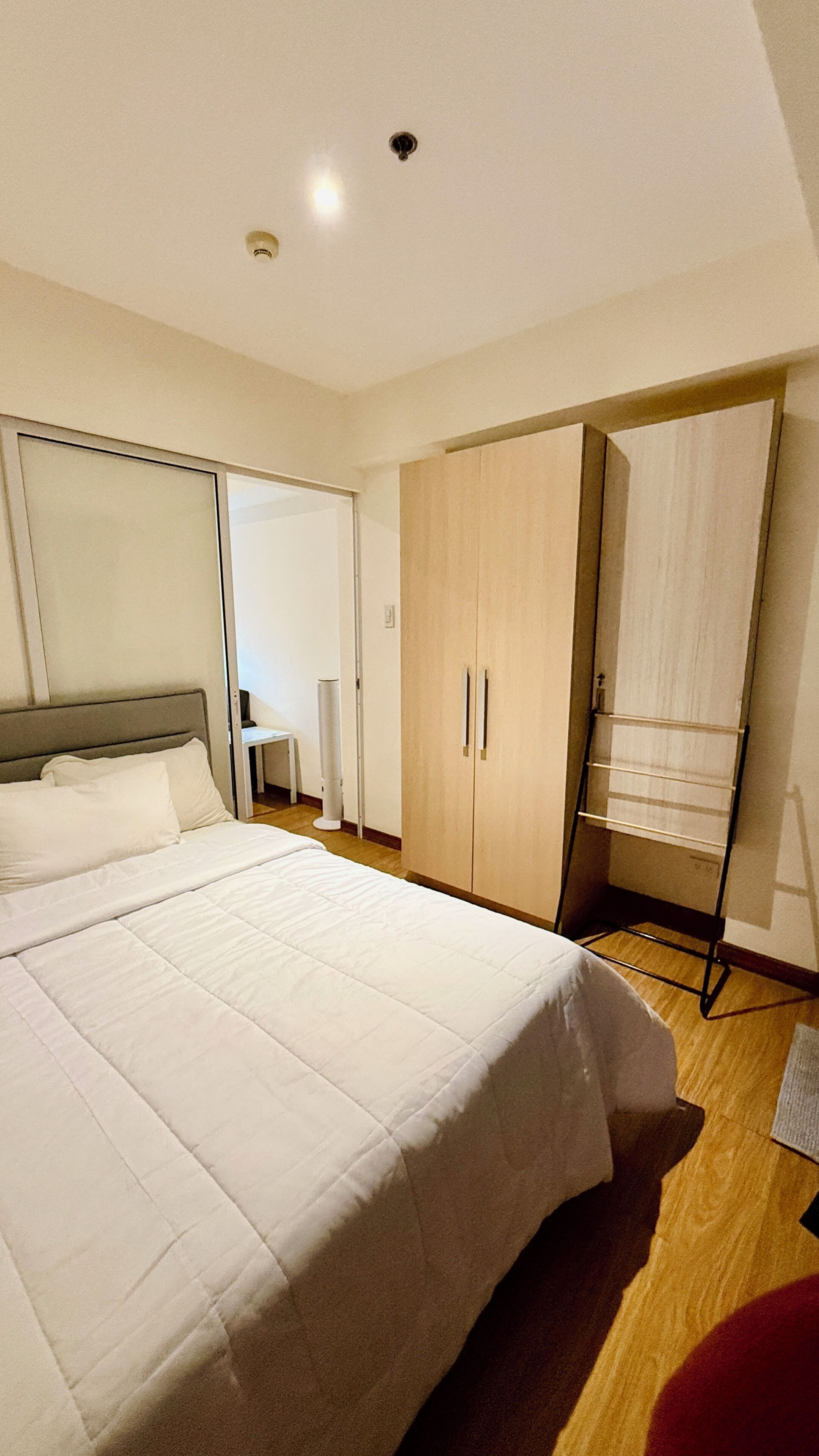 Een slaapkamer met een groot bed, een kledingkast en een plafondlamp.