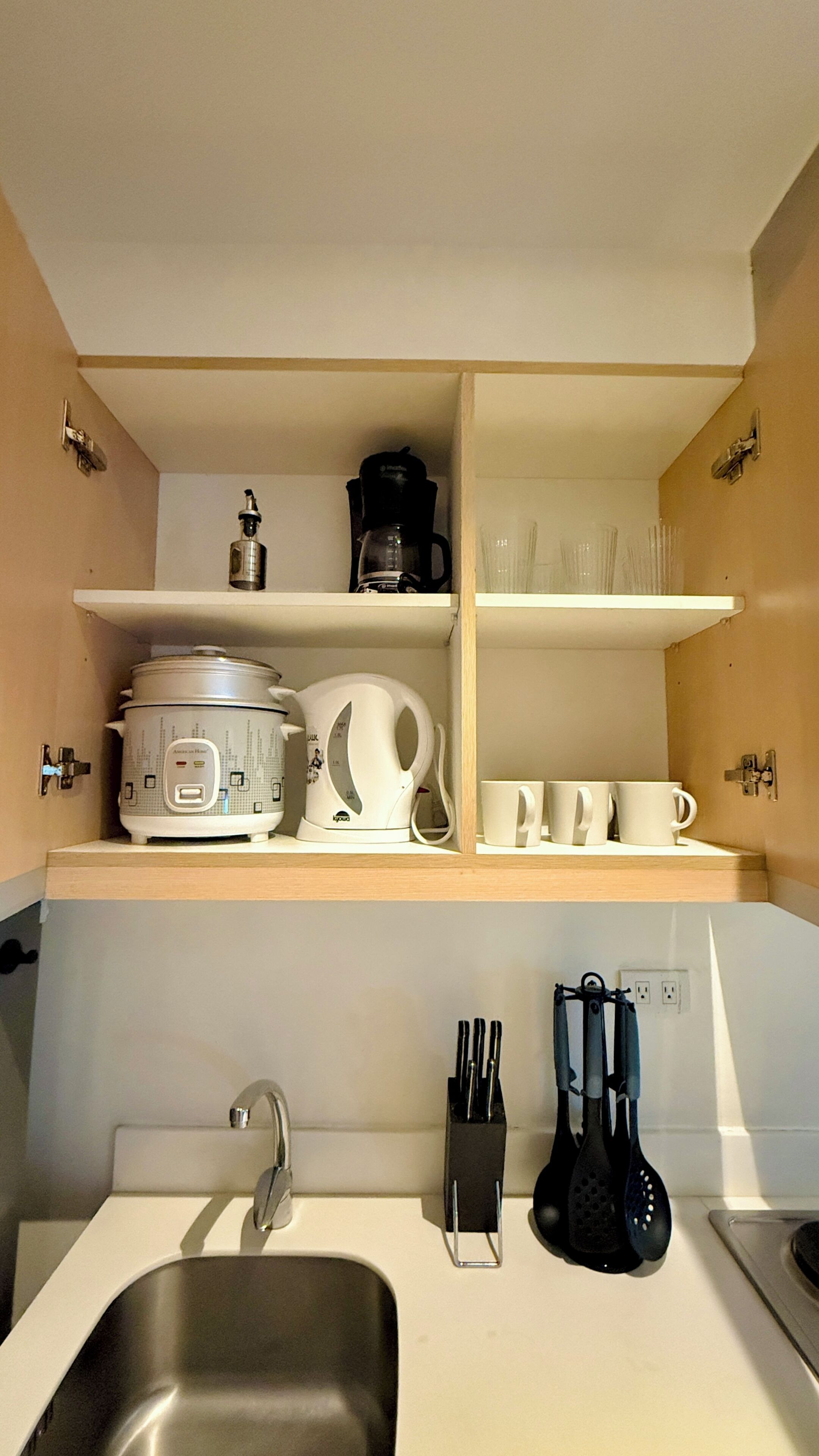 Een keuken met een spoelbak, een koffiezetapparaat, een waterkoker en een messenset.