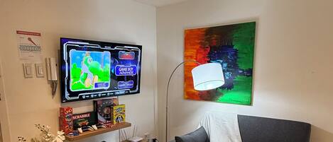 Una sala de estar con televisión, sofá, mesa de centro y un cuadro en la pared.