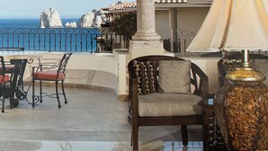 Una terrazza esterna con ventilatore a soffitto, tavolo e sedie, e vista sul mare.