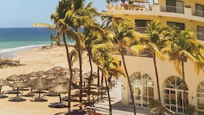 Un resort sulla spiaggia con piscina, palme e vista sull'oceano.