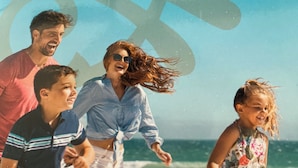 Una famiglia corre sulla spiaggia, con un grande logo di bicicletta sullo sfondo.