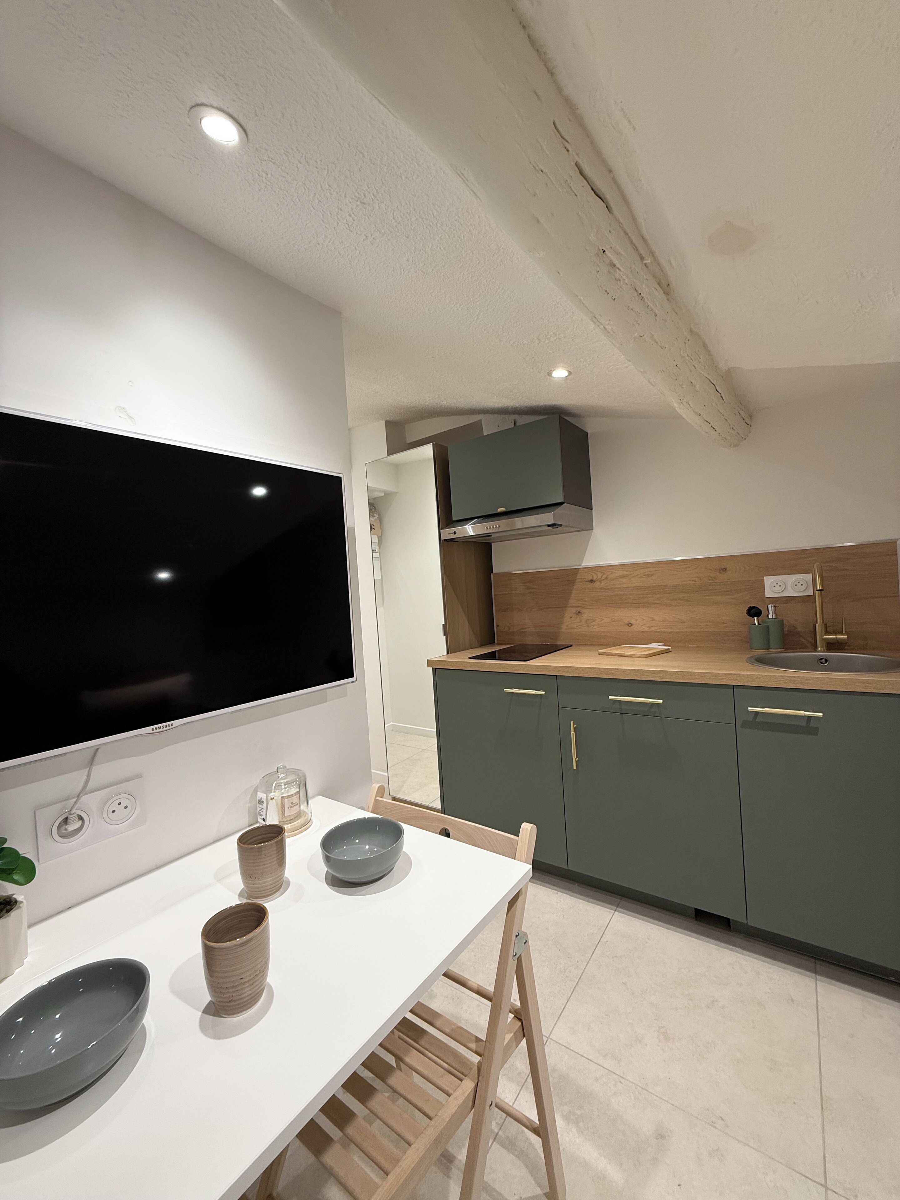 Eine moderne Küche mit großem Flachbildfernseher, Holzschränken und einem eingebauten Backofen.
