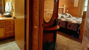 A wooden bedroom with a bed, a dresser, a mirror, and a ceiling fan. - Peaceful lakeside cedar cabin in charming Hot Springs (Hot Springs)