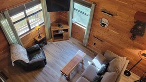 A cabin interior with a sofa, a small table, a leather chair, and a television. - Peaceful lakeside cedar cabin in charming Hot Springs (Hot Springs)
