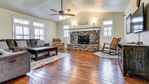 A spacious living room with a stone fireplace, hardwood flooring, and a ceiling fan. - Limpy Creek Access! Family Retreat in Grants Pass (Grants Pass)
