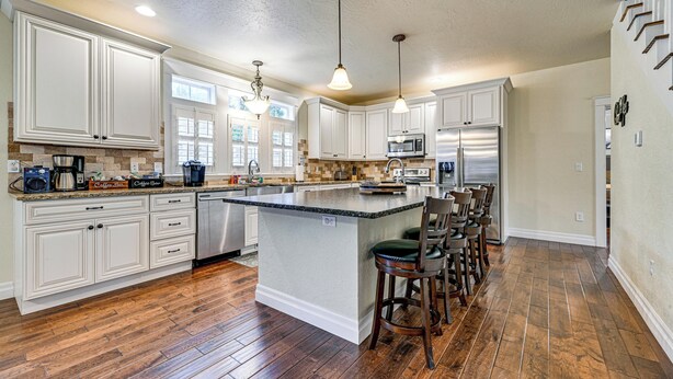 A spacious kitchen with white cabinetry, a large island with bar stools, a microwave, and a refrigerator. - Limpy Creek Access! Family Retreat in Grants Pass (Grants Pass)