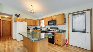 A kitchen with wooden cabinets, a refrigerator, a stove, and a microwave.