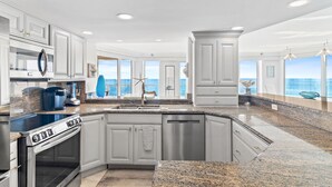Una cocina moderna con encimeras de granito, electrodomésticos de acero inoxidable y armarios blancos.