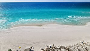 Una playa con aguas turquesas cristalinas, una orilla arenosa y algunas estructuras al frente.