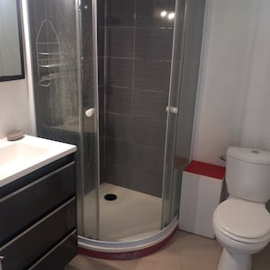 A bathroom with a glass-enclosed shower, a white toilet, and a sink with a dark countertop. - Functional duplex with superb sea view (Les Trois-Îlets)