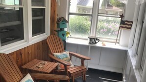 A cozy room with wooden furniture, including a bench and chairs, near a window with a view of greenery outside. - Quaint 2-bedroom house wanting your TLC in charming Hammondsport (Hammondsport)