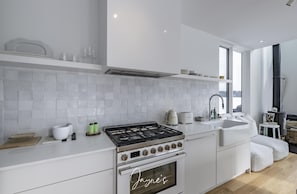Une cuisine moderne avec des meubles blancs, une cuisinière à gaz et une grande fenêtre offrant une vue dégagée.