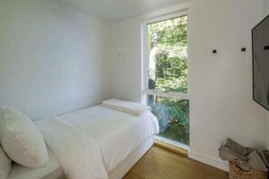 A bedroom with a single bed, a window with a view of greenery, and a wall-mounted television. - Unique 2+ bed 3+ bath Lake Rosseau cottage on the water (Minett)