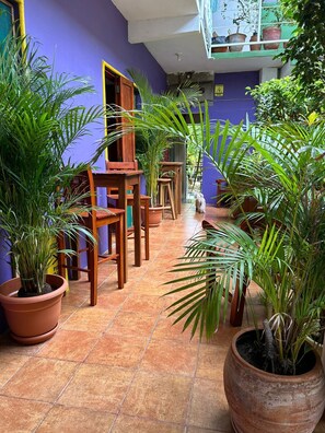 A room with a tiled floor, wooden furniture, and potted plants. - Casa Romano Hostal (San Juan del Sur)