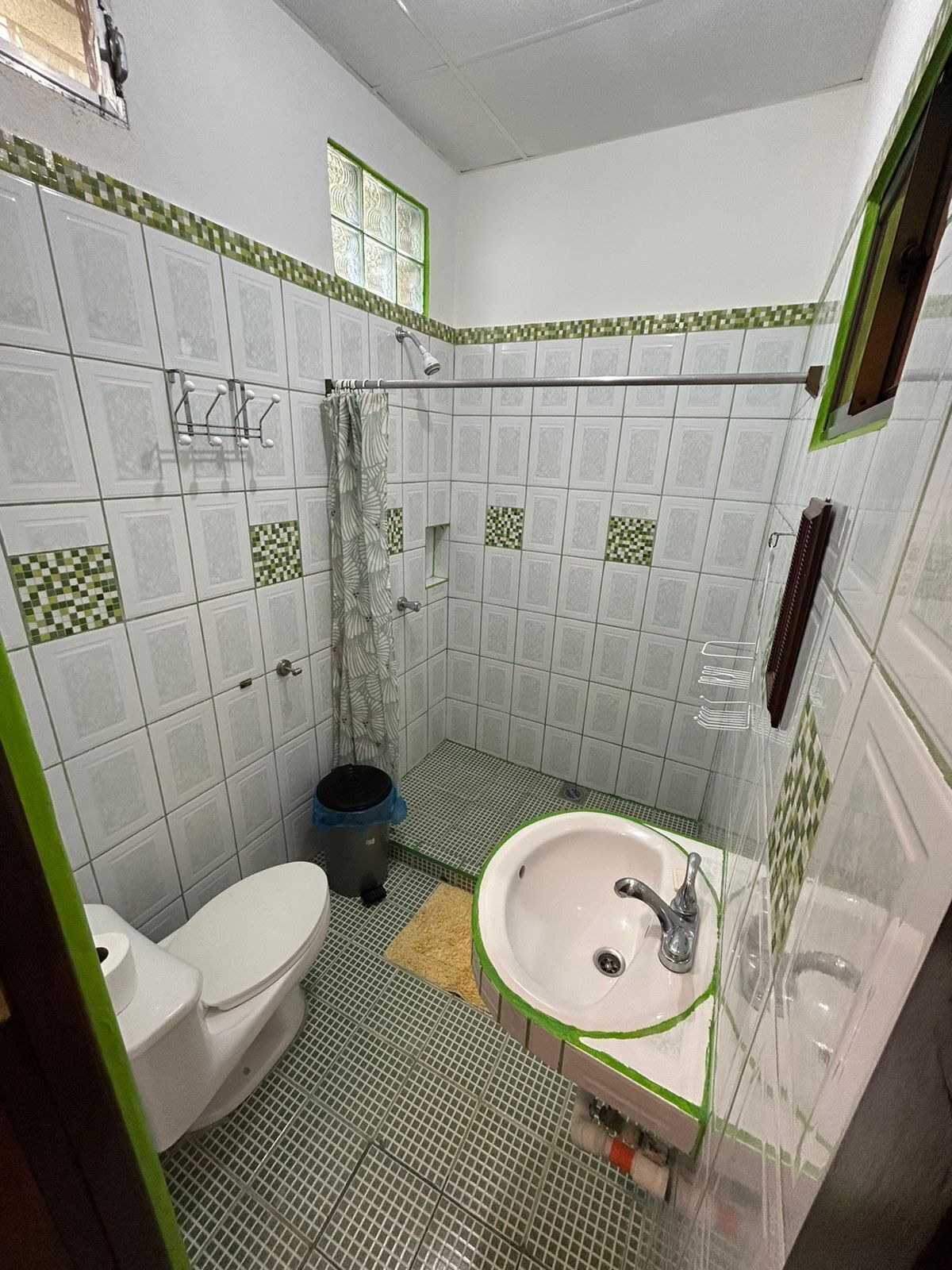 Ein Badezimmer mit Toilette, Waschbecken, Dusche und Fliesenwänden.