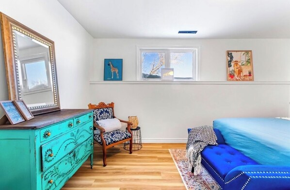 A bedroom with a turquoise dresser, a blue sofa, and a large mirror. - Private Basement Suite | Minutes to Downtown (Charlottetown)