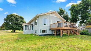 Une maison à deux étages avec une terrasse en bois et un petit garage attenant.