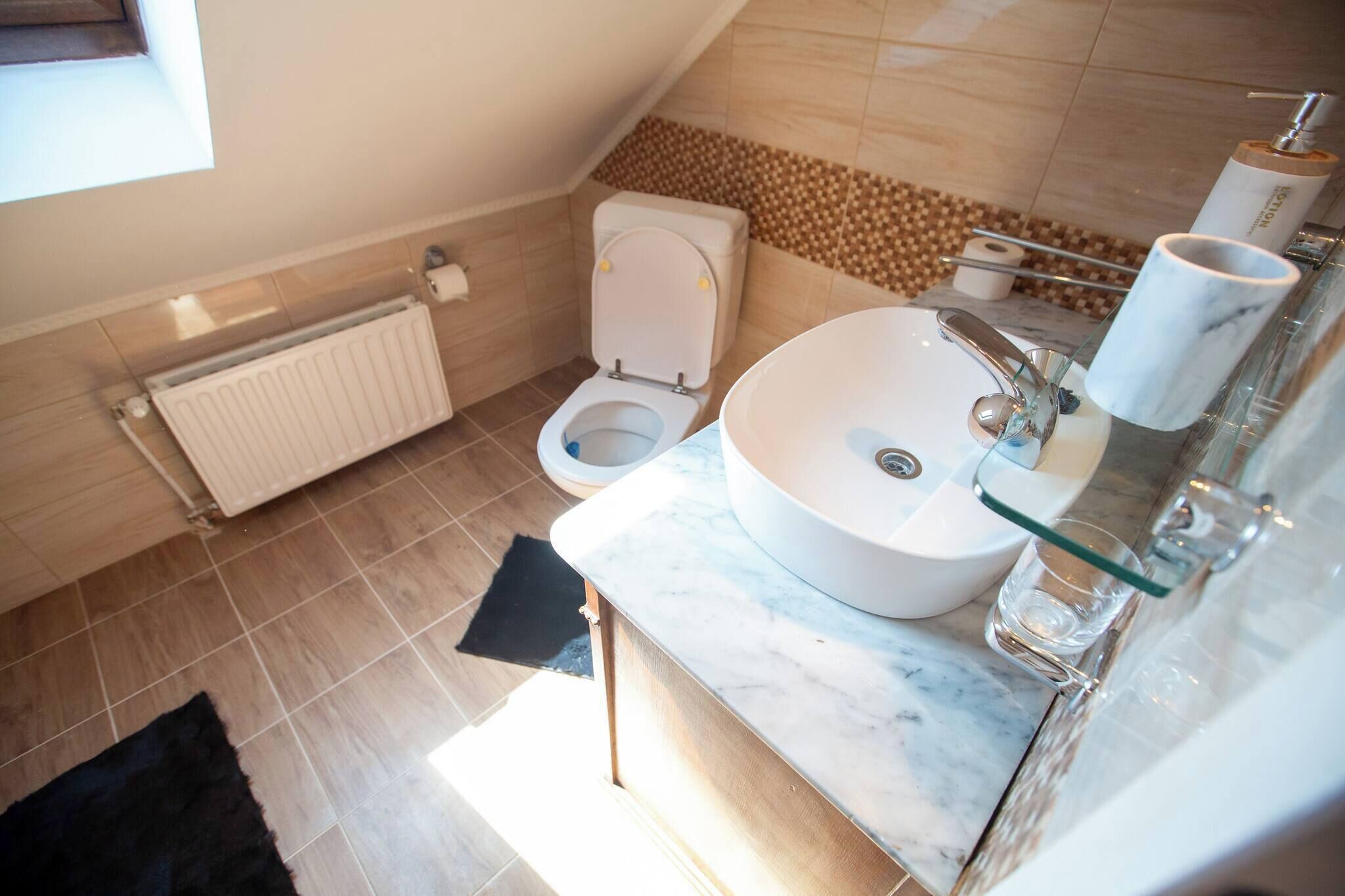 A modern bathroom with a white toilet, a large sink, and a glass shower enclosure.