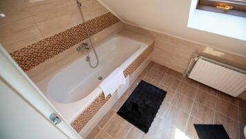 Ein Badezimmer mit einer Badewanne, einer Dusche und einem Fenster.