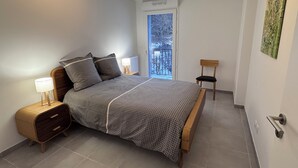 A bedroom with a bed, bedside table, chair, and a window with a view of trees. - New apartment near Prorel (Briançon)