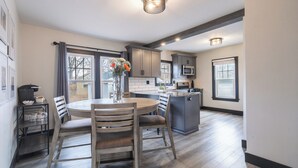 Una cocina moderna con una isla central, muebles oscuros y un comedor con una mesa redonda y sillas.