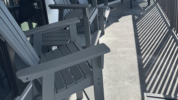 Un balcone con poltrone Adirondack, vista sull'oceano e cielo sereno.