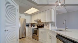 Una cucina moderna con mobili bianchi, un frigorifero in acciaio inossidabile, forno integrato e lavastoviglie.
