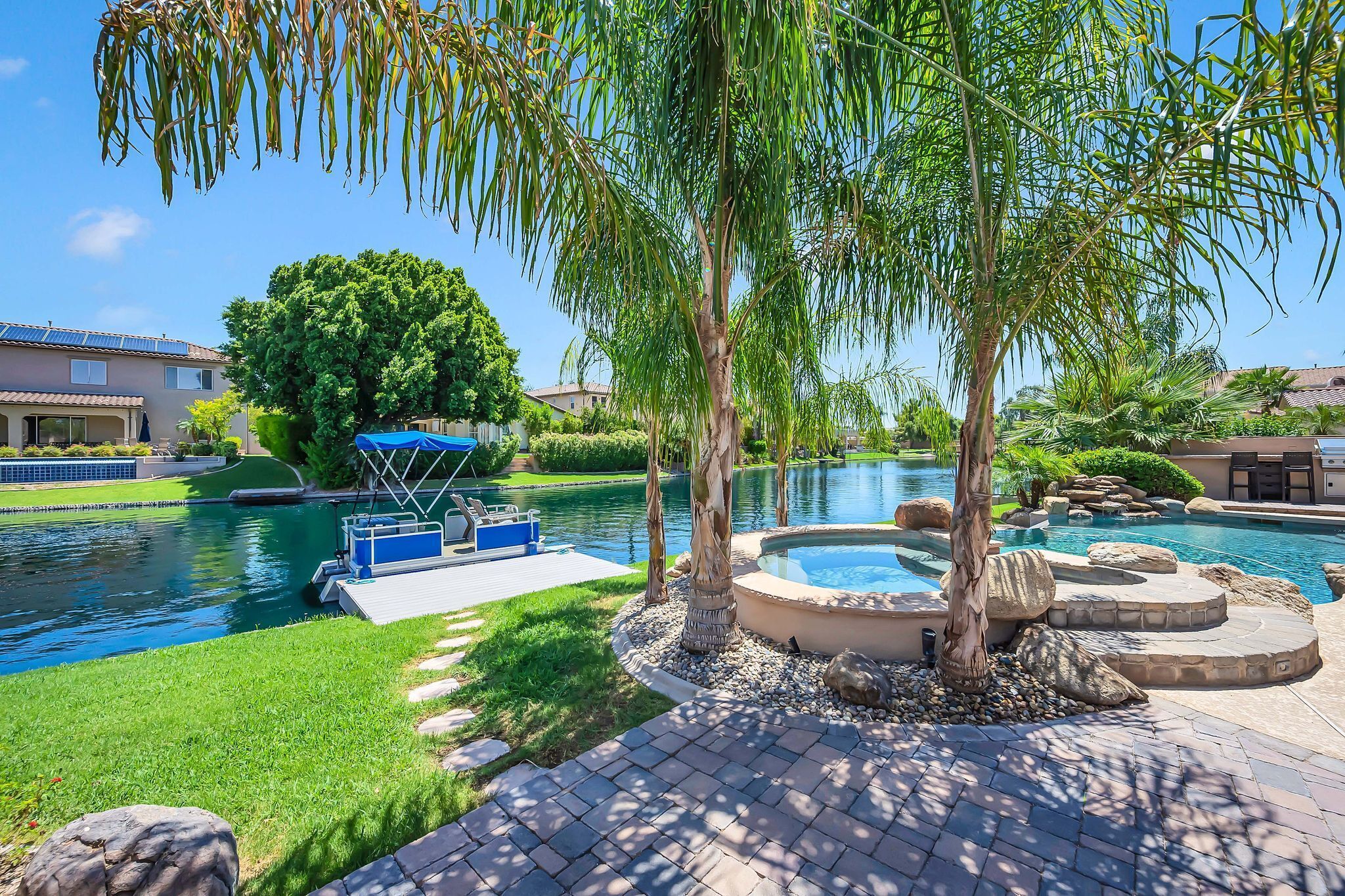 A swimming pool area with a hot tub, lounge chairs, and a covered seating area.