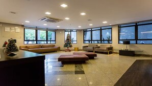 Un vestíbulo amplio con mostrador de recepción, zona de estar y ventanas grandes que ofrecen vistas al exterior.