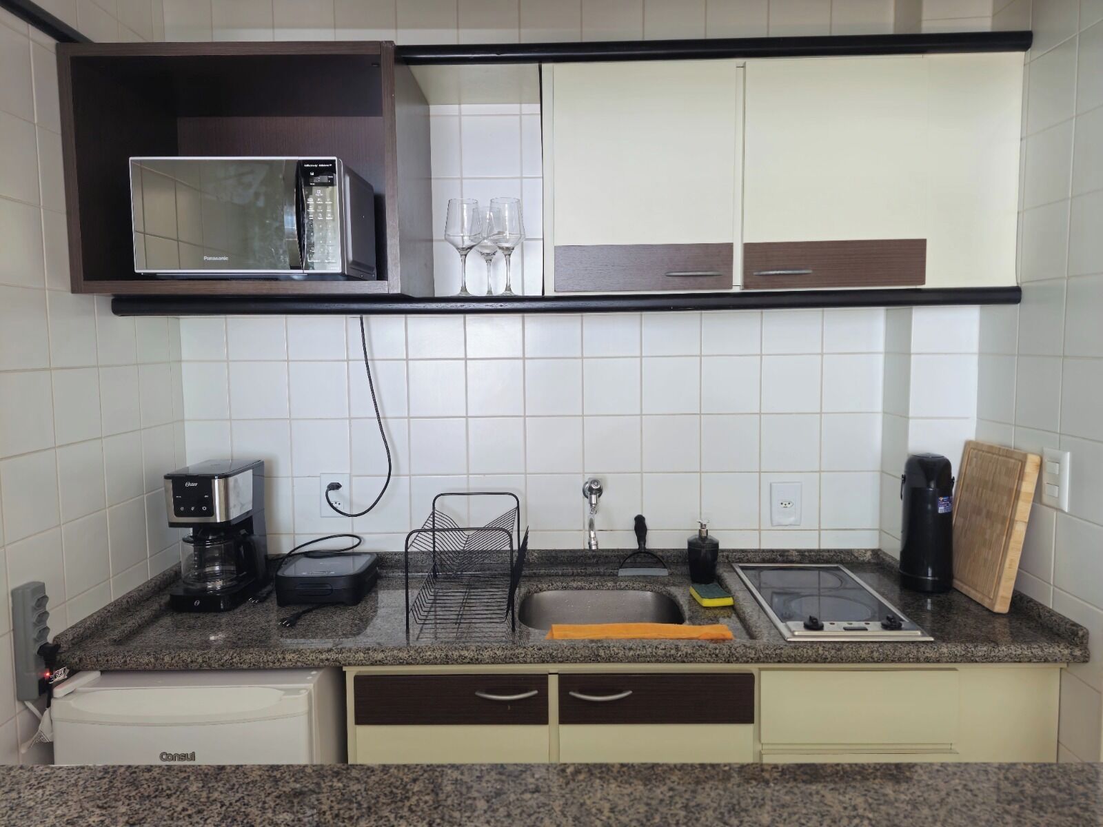 A compact kitchen with a microwave, coffee maker, sink, and a small countertop area.