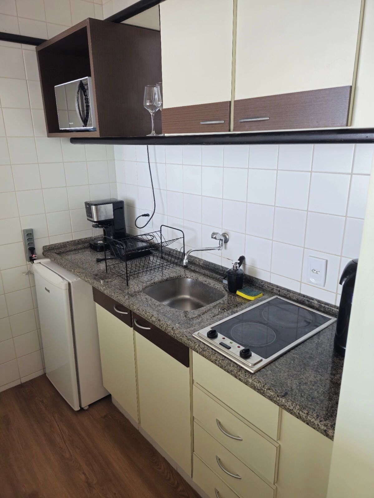 A compact kitchen with a built-in microwave, a coffee maker, a sink, and a stove.