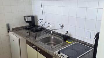 A compact kitchen with a built-in microwave, a coffee maker, a sink, and a stove.
