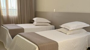 A hotel room with two beds, each with a white bedspread and a brown blanket. - HOTEL DUNAMYS (Londrina)