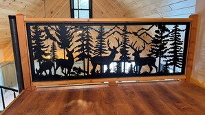 A room with a wooden ceiling, a window, and a framed silhouette artwork of deer and trees.