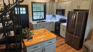 A kitchen with a wooden countertop, stainless steel appliances, and light-colored cabinets.