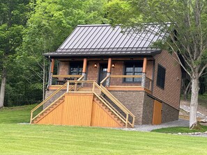 A cabin with a wooden staircase leading to a porch, surrounded by trees. - Welcome to “The Old Orchard Cottage”. A cozy 2-bedroom cabin in LaFayette, NY.  (LaFayette)
