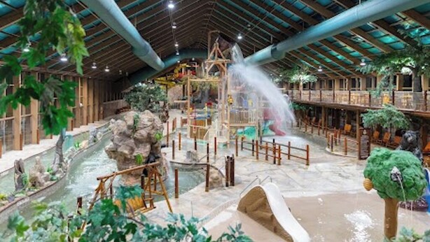 An indoor water park with a central water feature, wooden play structures, and a covered roof with visible beams. - Relax in Gatlinburg w/cool mountain views, FUN activities for all in the family! (Gatlinburg)