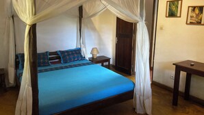 A bed with a blue mattress and white canopy, a wooden nightstand, and a small table.