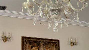 Un candelabro con múltiples brazos y decoraciones de cristal, un cuadro enmarcado de dos figuras en la pared, y apliques montados en la pared.
