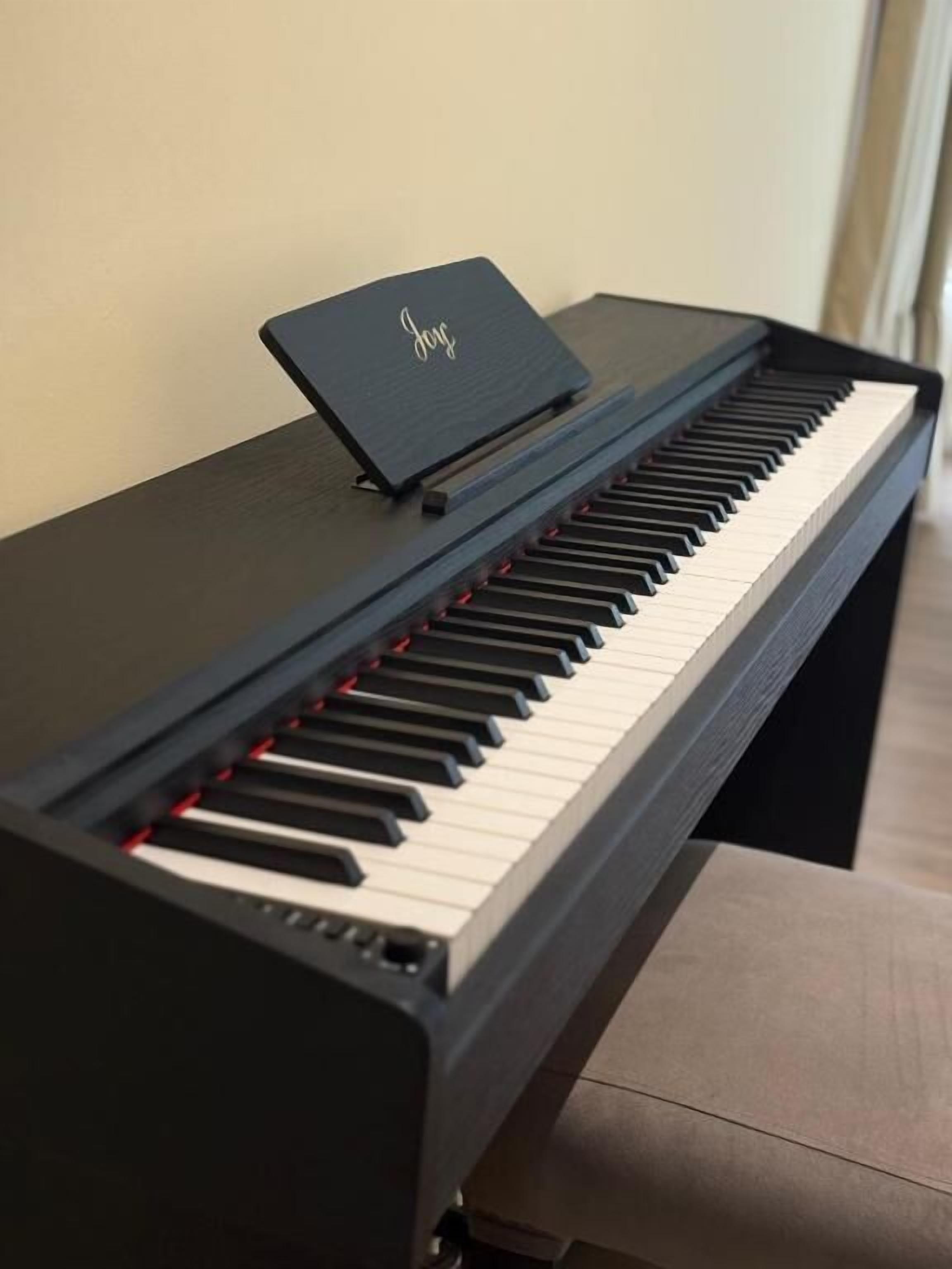 Un piano noir à queue, doté d’un pupitre à partitions sur lequel est inscrit le mot « Joie ».