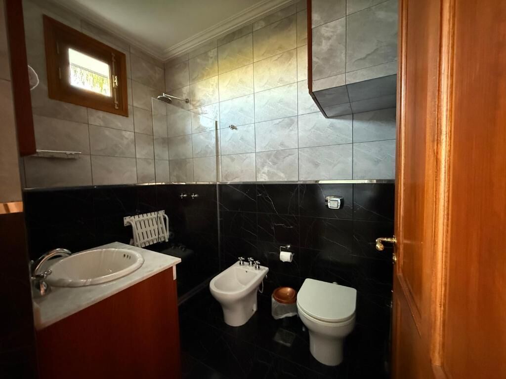 A bathroom with a bathtub, bidet, toilet, and a small window.