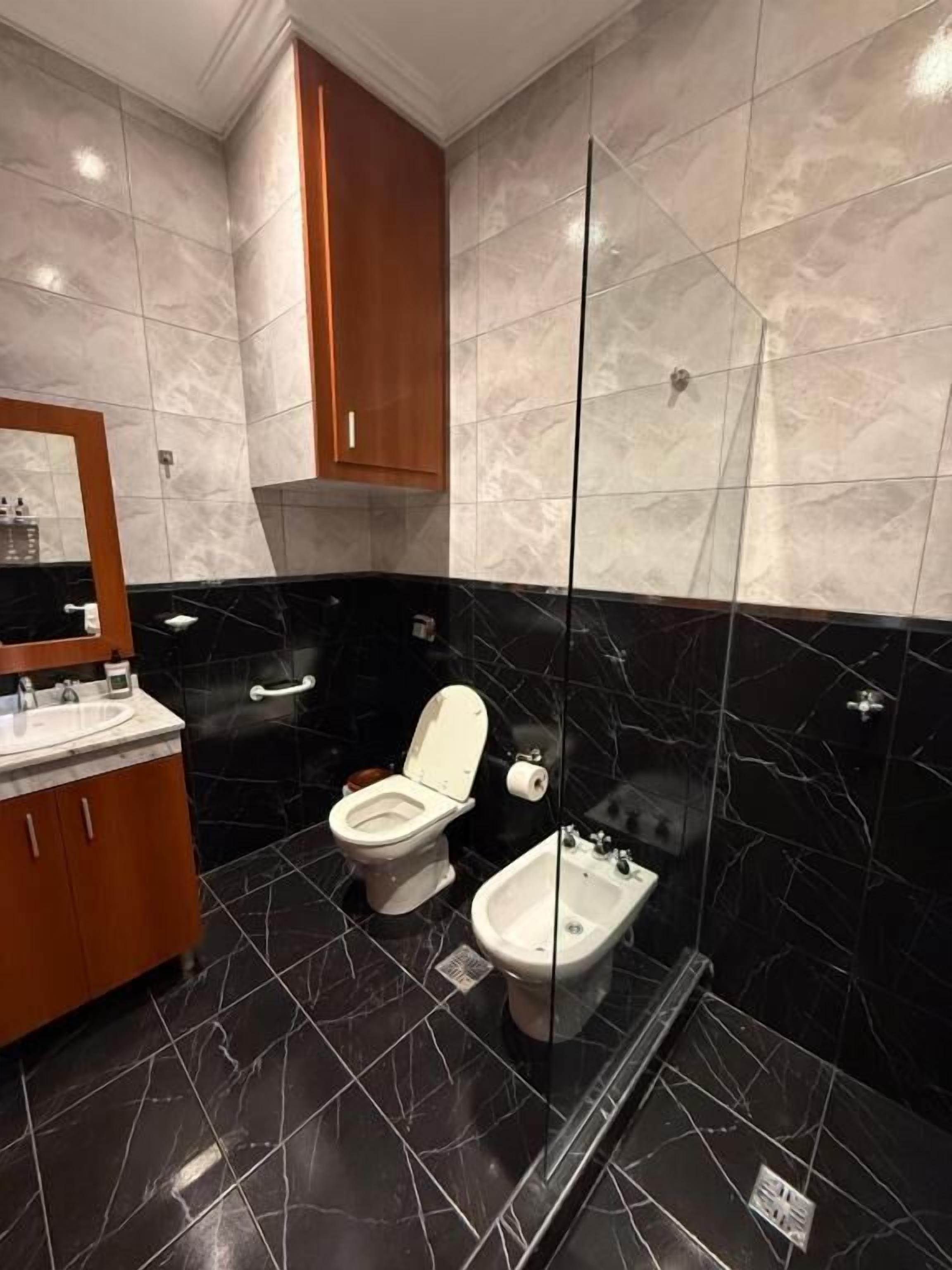 Un baño moderno con inodoro, bidé y tocador con espejo.