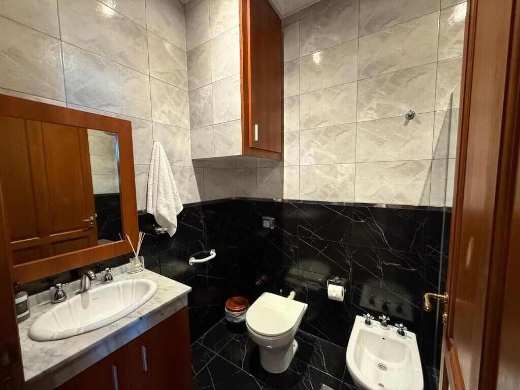 Un baño con lavamanos, inodoro, bidé y espejo.