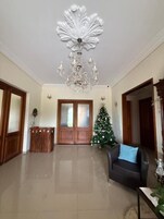 Uma sala de estar ampla com um candelabro, uma árvore de Natal e um sofá.